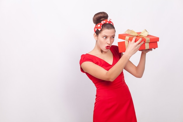 Mujer astuta, mirando dentro de la caja de regalo. Interior, tiro del estudio, aislado en fondo gris