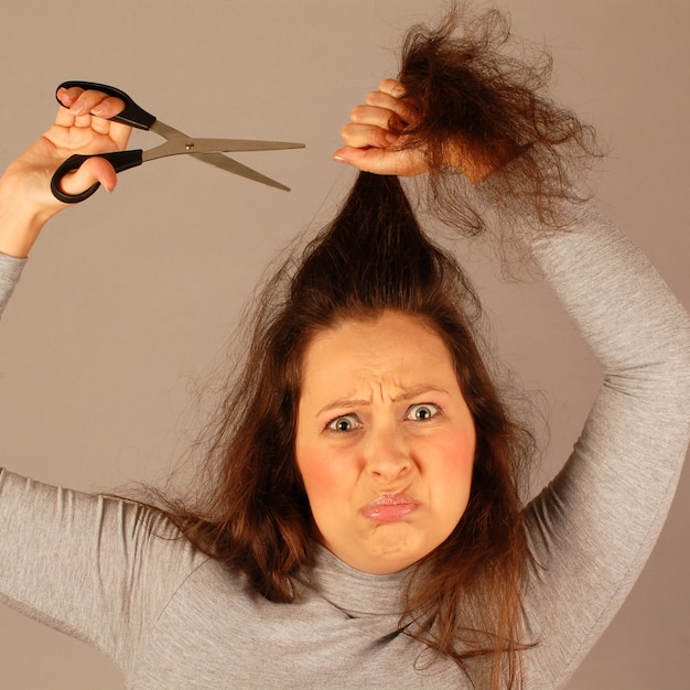 Foto la mujer asustada se está cortando el pelo.