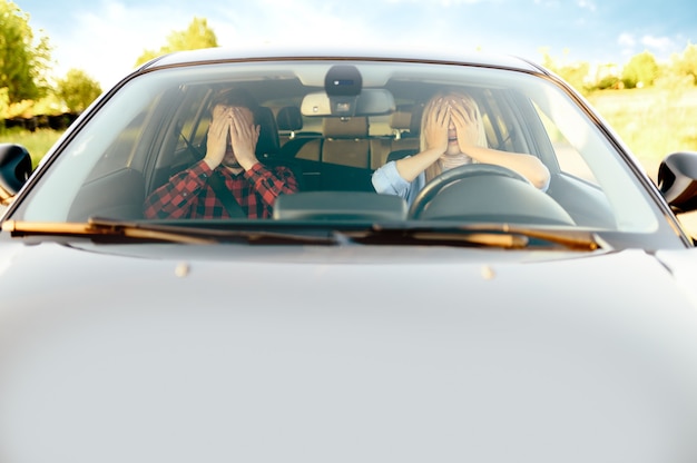 Mujer asustada e instructor en coche, vista frontal, autoescuela. Hombre enseñando a la señora a conducir un vehículo. Educación sobre licencia de conducir, situación de accidente