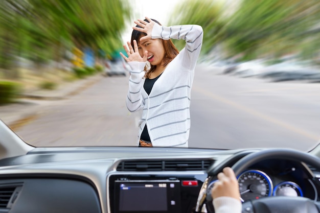 Foto mujer asustada frente al coche vista a través del parabrisas