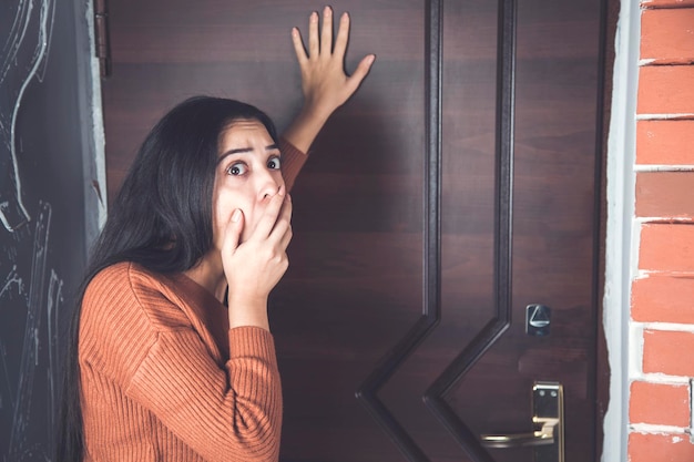 Mujer asustada con la mano en la puerta