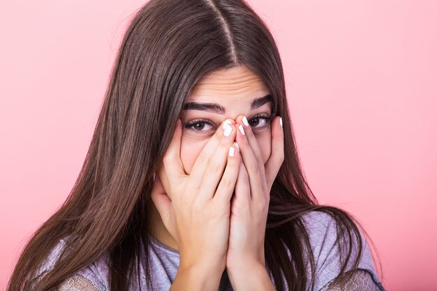 Mujer asustada manteniendo las manos sobre su rostro y mirando a cámara