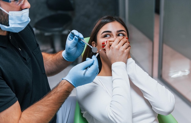 Una mujer asustada tiene una visita en la clínica del dentista. Concepción de la estomatología.