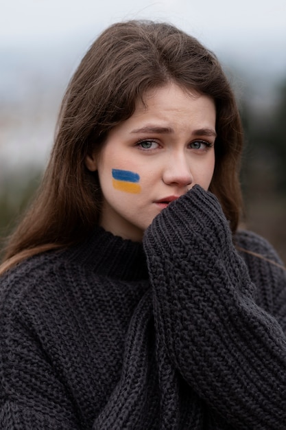 Mujer asustada de tiro medio con dibujo de bandera ucraniana