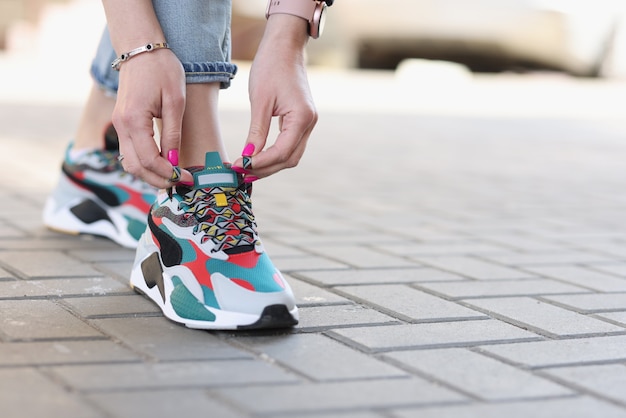 Mujer atar cordones de zapatillas deportivas closeup