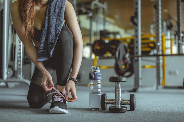 Mujer atar los cordones de los zapatos en gymyoung hembra en el gimnasio tomando un descanso del entrenamiento de fitness gimnasio