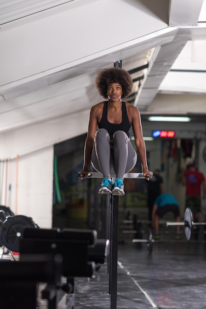 Mujer atleta afroamericana entrena los brazos en salsas barras paralelas horizontales Ejercicio entrenamiento tríceps y bíceps haciendo flexiones