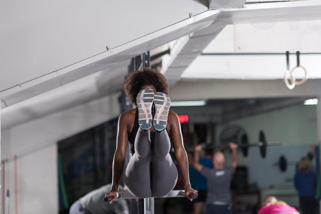 Mujer atleta afroamericana entrena los brazos en salsas barras paralelas horizontales Ejercicio entrenamiento tríceps y bíceps haciendo flexiones
