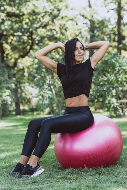 Mujer atleta con una gran pelota de fitness entrena en el parque