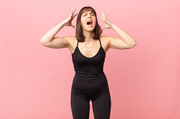 Foto mujer atleta gritando con las manos en alto, sintiéndose furiosa, frustrada, estresada y molesta