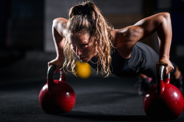 Mujer atleta haciendo ejercicio con pesas rusas