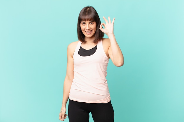 Mujer atleta que se siente feliz, relajada y satisfecha, mostrando aprobación con un gesto aceptable, sonriendo