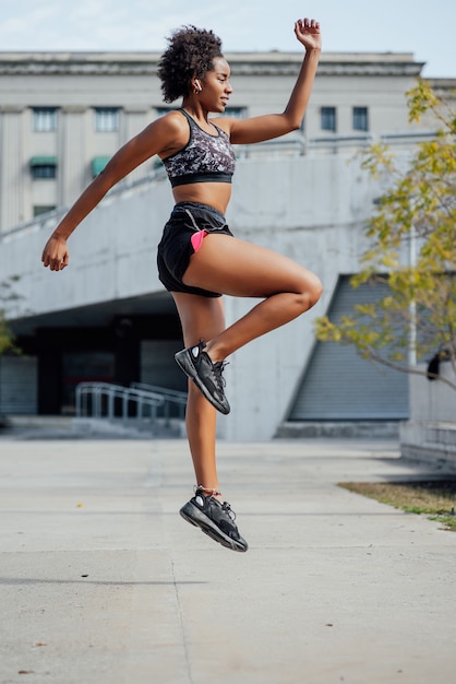 Mujer atlética afro haciendo ejercicio al aire libre en la calle. Concepto de deporte y estilo de vida saludable.