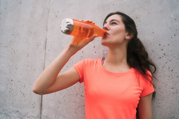 Mujer atlética agua potable después del entrenamiento.