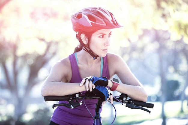 Mujer atlética apoyándose en bicicleta en campo