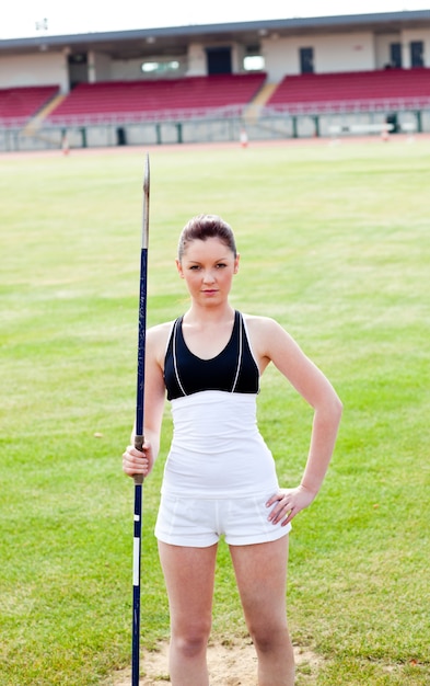 Mujer atlética confiada lista para lanzar una jabalina que se coloca en un estadio