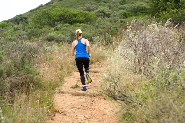 Mujer atlética corriendo en camino de tierra fuera