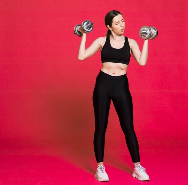 Mujer atlética feliz Foto de mujer deportiva en ropa deportiva negra de moda sobre fondo rojo