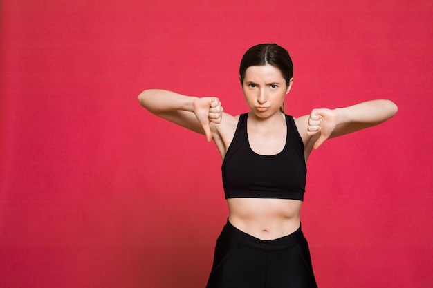 Mujer atlética feliz Foto de mujer deportiva en ropa deportiva negra de moda sobre fondo rojo