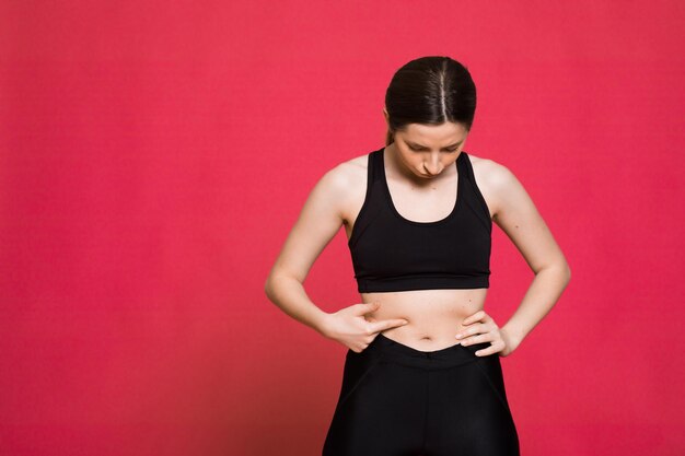 Mujer atlética feliz Foto de mujer deportiva en ropa deportiva negra de moda sobre fondo rojo