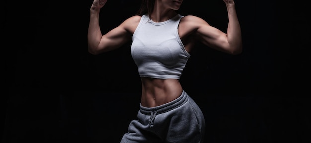 Mujer atlética fitness posando en el estudio sobre un fondo oscuro Foto de una mujer atractiva en ropa deportiva de moda Deportes y estilo de vida saludable