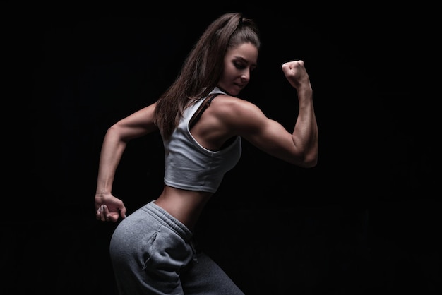 Mujer atlética fitness posando en el estudio sobre un fondo oscuro Foto de una mujer atractiva en ropa deportiva de moda Deportes y estilo de vida saludable