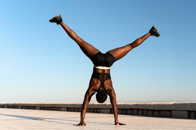 Mujer atlética en forma haciendo mano de pie en la playa