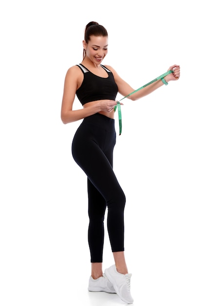 Mujer atlética fuerte y delgada que mide los abdominales sobre fondo blanco aislado