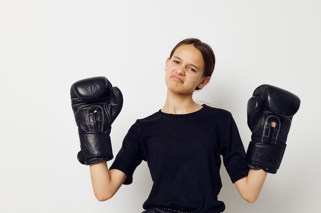 Mujer atlética en guantes de boxeo uniformes deportivos negros posando fondo aislado