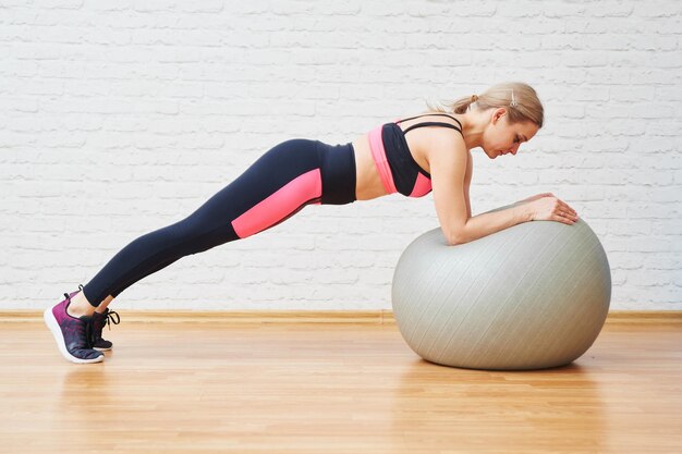 Mujer atlética haciendo ejercicios saludables con pelota de fitness aislada en el fondo de la pared Entrenamiento en casa y en el gimnasio Pilates