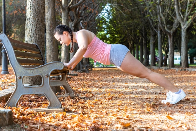 Mujer atlética haciendo flexiones en la calle en otoño concepto de estilo de vida saludable