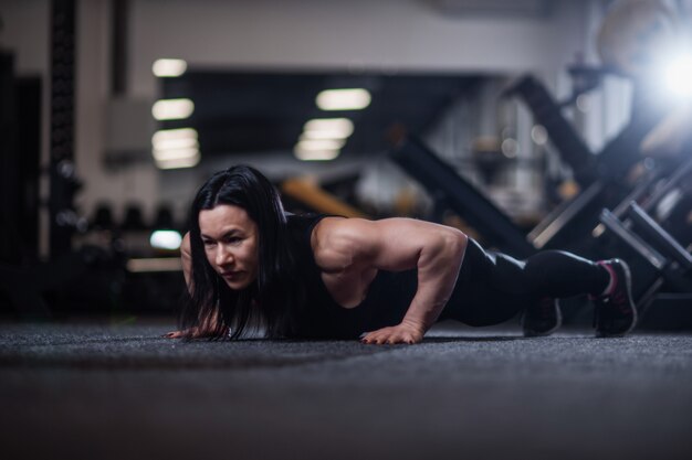 Mujer atlética haciendo flexiones en el gimnasio