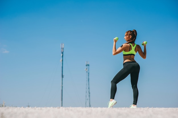 mujer atlética inflar los músculos con pesas