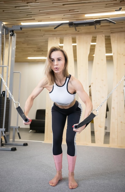 Mujer atlética joven que hace ejercicios de fuerza en las manos en el gimnasio