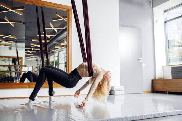 Mujer atlética joven que tiene clase de yoga aérea en estudio de estiramiento durante el día Concepto de estilo de vida saludable