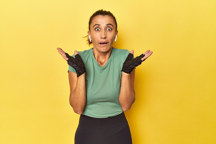 Foto mujer atlética de mediana edad sobre fondo amarillo sorprendida y consternada