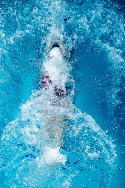 Mujer atlética nadando en la espalda con piscina