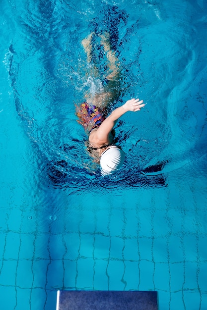 Mujer atlética nadando con gorro de baño y gafas en la piscina