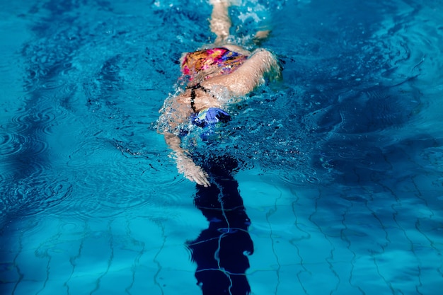 Mujer atlética nadando con gorro de baño y gafas en la piscina