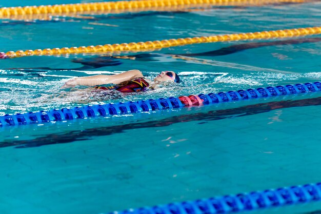Mujer atlética nadando con gorro de baño y gafas en la piscina