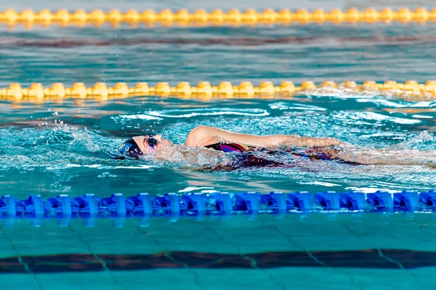 Mujer atlética nadando con gorro de baño y gafas en la piscina