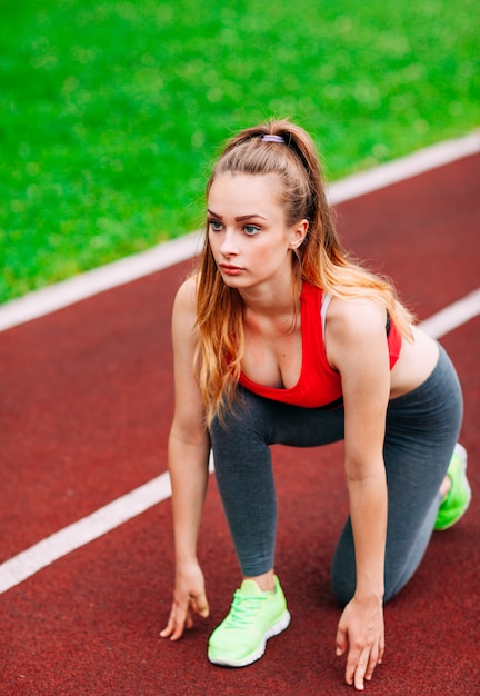 Mujer atlética en pista empezando a correr. Concepto de fitness saludable con estilo de vida activo.