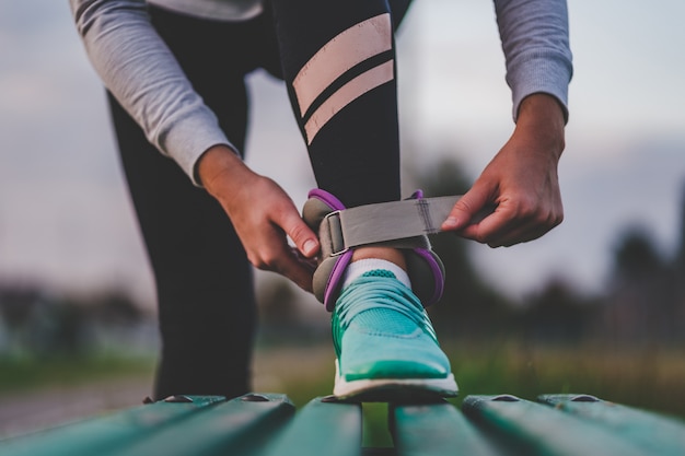 La mujer atlética pone pesas deportivas para caminar durante el entrenamiento al aire libre. Estilo de vida saludable y deportivo.