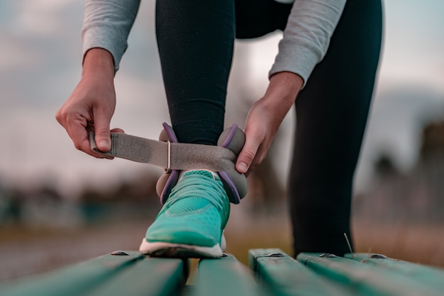 La mujer atlética pone pesas deportivas para caminar durante el entrenamiento al aire libre. Estilo de vida saludable y deportivo.