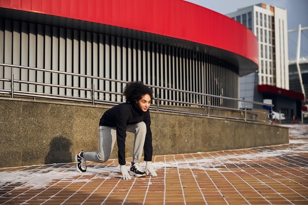 Mujer atlética en posición inicial en una plaza