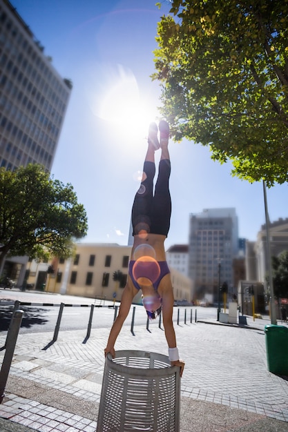 Mujer atlética realizando handstand en bin