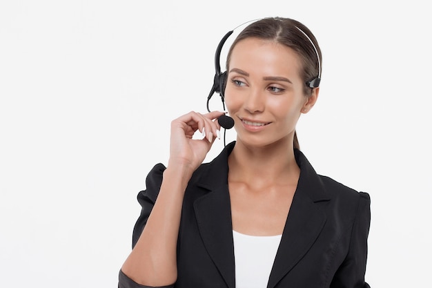 Mujer atractiva aislada en traje negro con auriculares mirando hacia otro lado