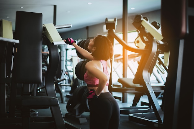 Mujer atractiva del ajuste que se relaja después del entrenamiento en aptitud del gimnasio