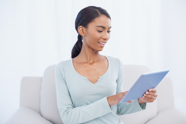 Mujer atractiva alegre que usa su tableta digital