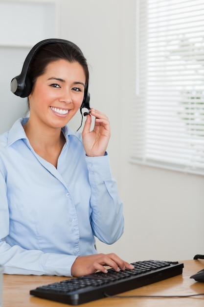 Mujer atractiva con un auricular ayudar a los clientes mientras está sentado